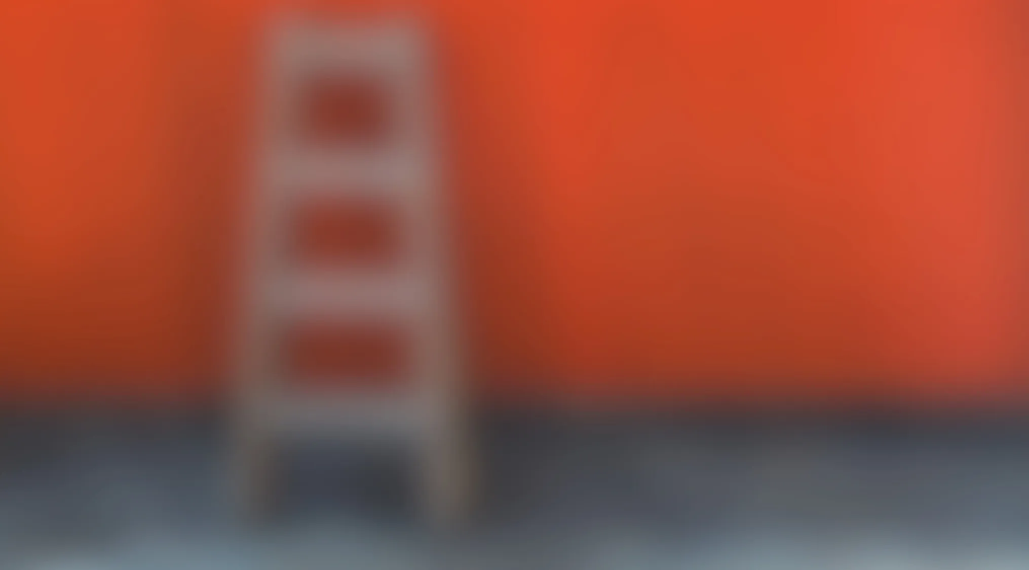 Blurry image of a common household item with an orange wall and gray floor background.