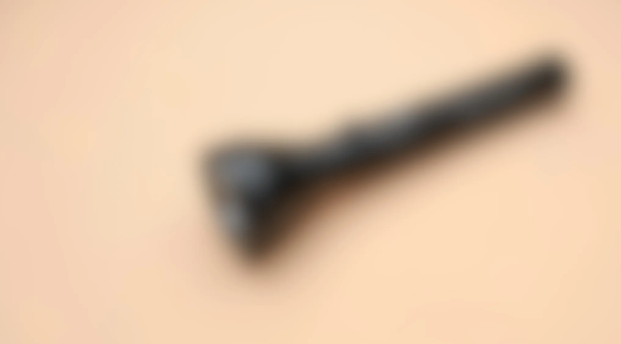 Blurry image of a common household object with a long handle against a beige background