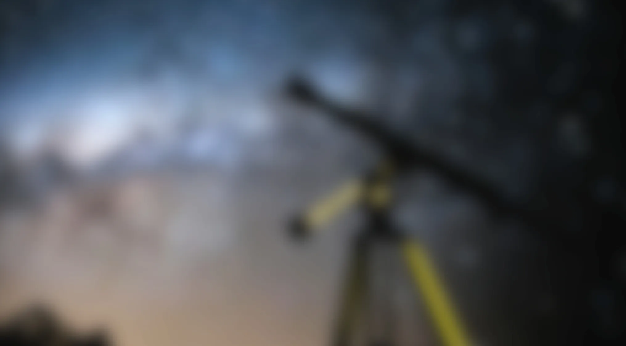 Blurry image showing an indistinct object against a gradient sky with dark silhouettes in the background.