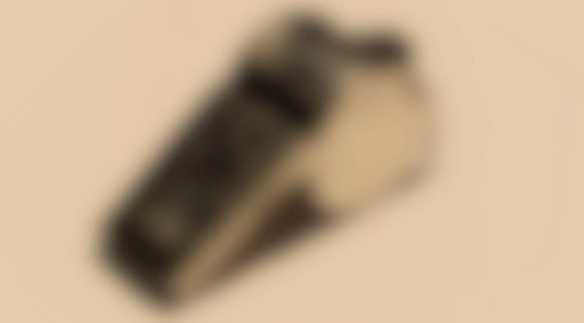 Blurry image of a common object, slightly angled on a beige background, challenging identification through blur effect.