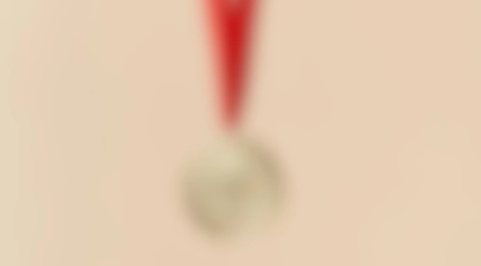 Blurry image showing an indistinct round object hanging from a red string on a beige background