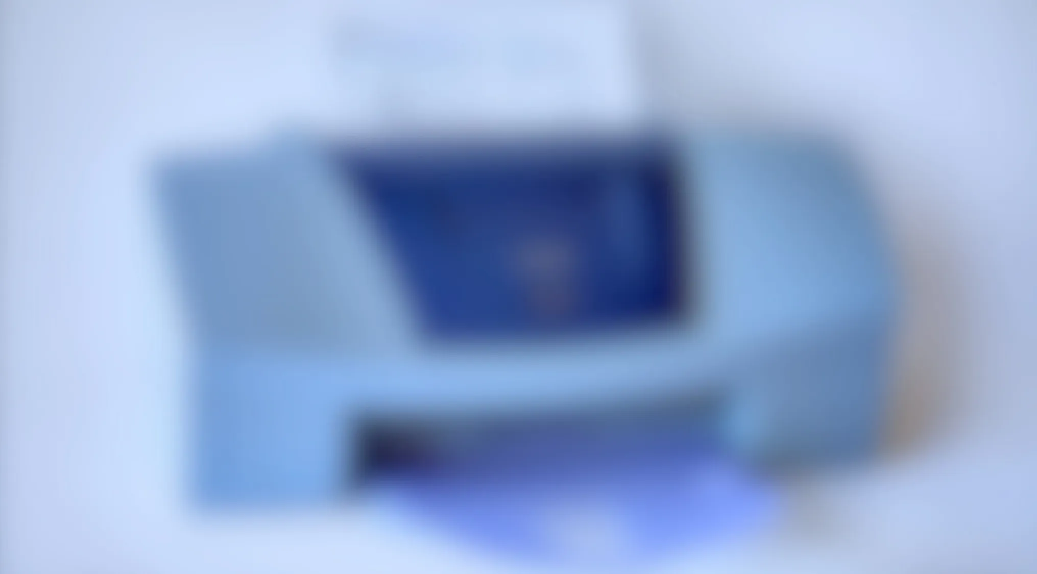 Blurry image of a common device resembling a home printer with blue tones and indistinct details.