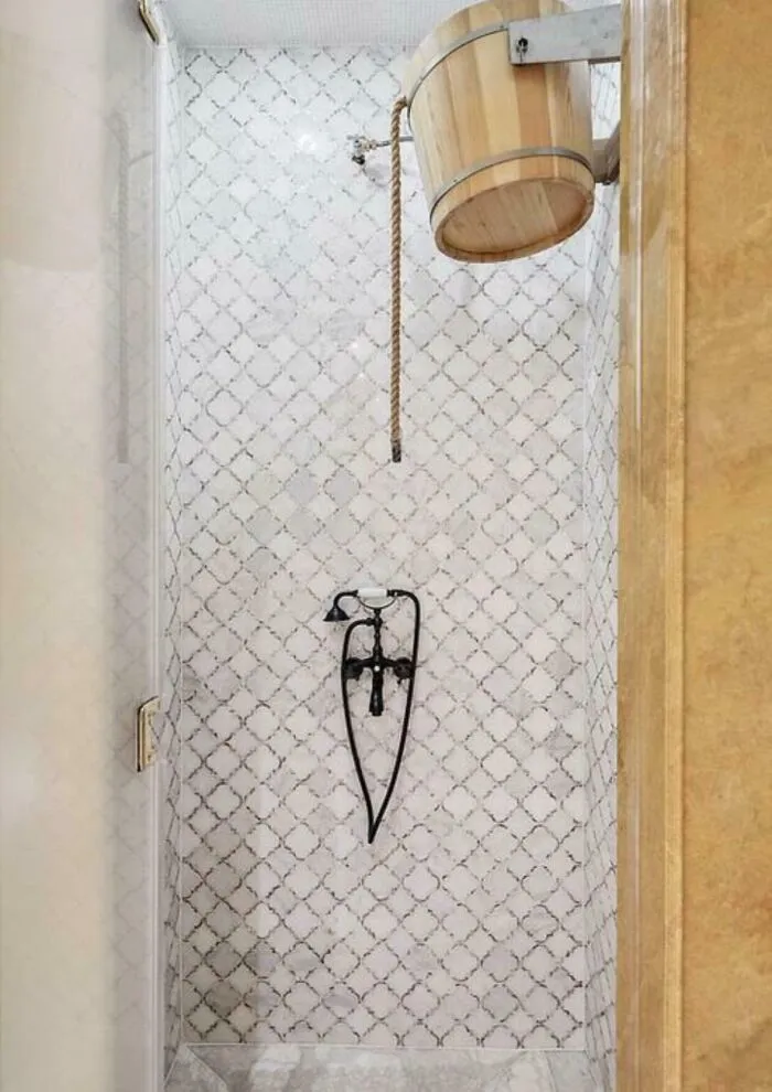 Wooden bucket shower with rope pull and vintage black metal shower fixture in a tiled bathroom, unidentified objects solved by internet.