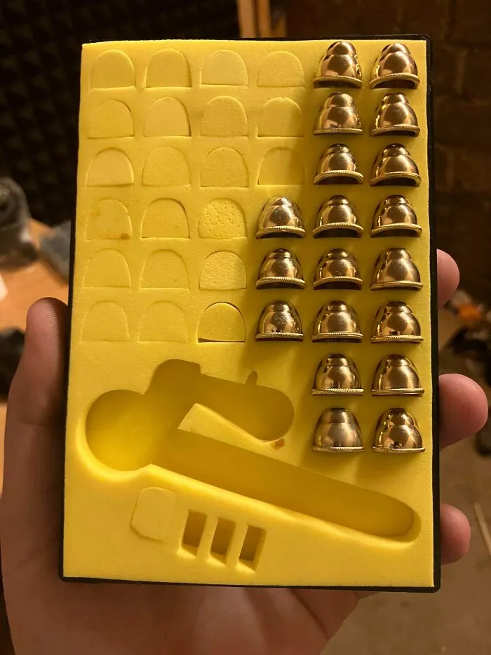 Hand holding yellow foam case with metal thimbles and cutouts, an example of the internet solving the mystery of unidentified objects.
