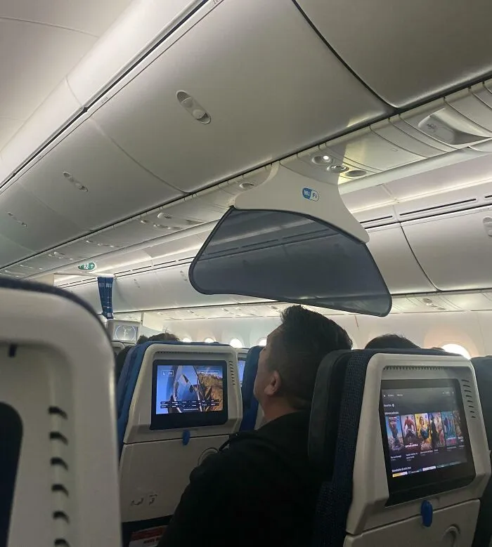 Passenger sitting inside airplane cabin with entertainment screens, an example of the internet solving mystery of unidentified objects.
