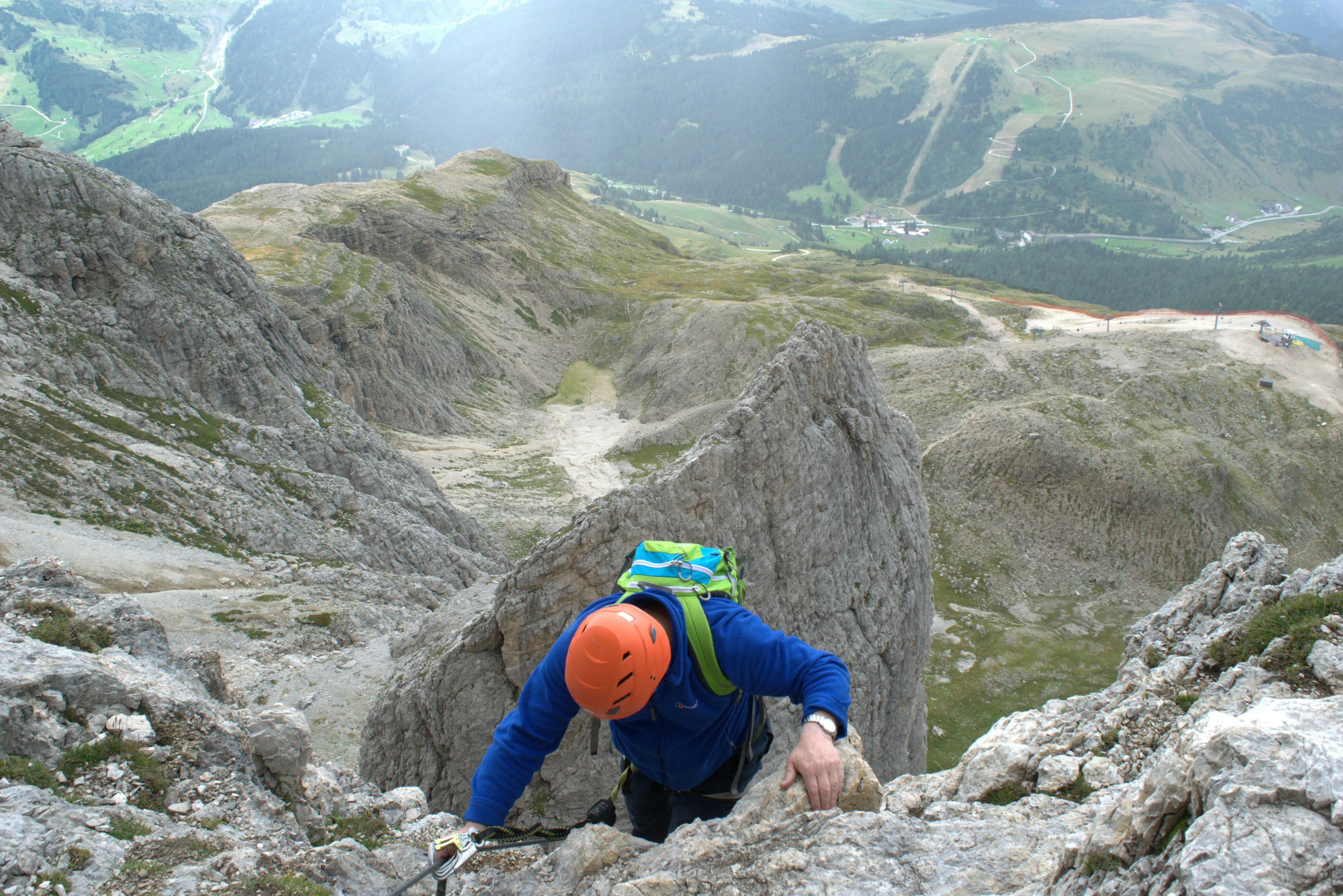 Man climbing steep rocky mountain wearing helmet and backpack, illustrating effects of high-altitude acclimatizing.