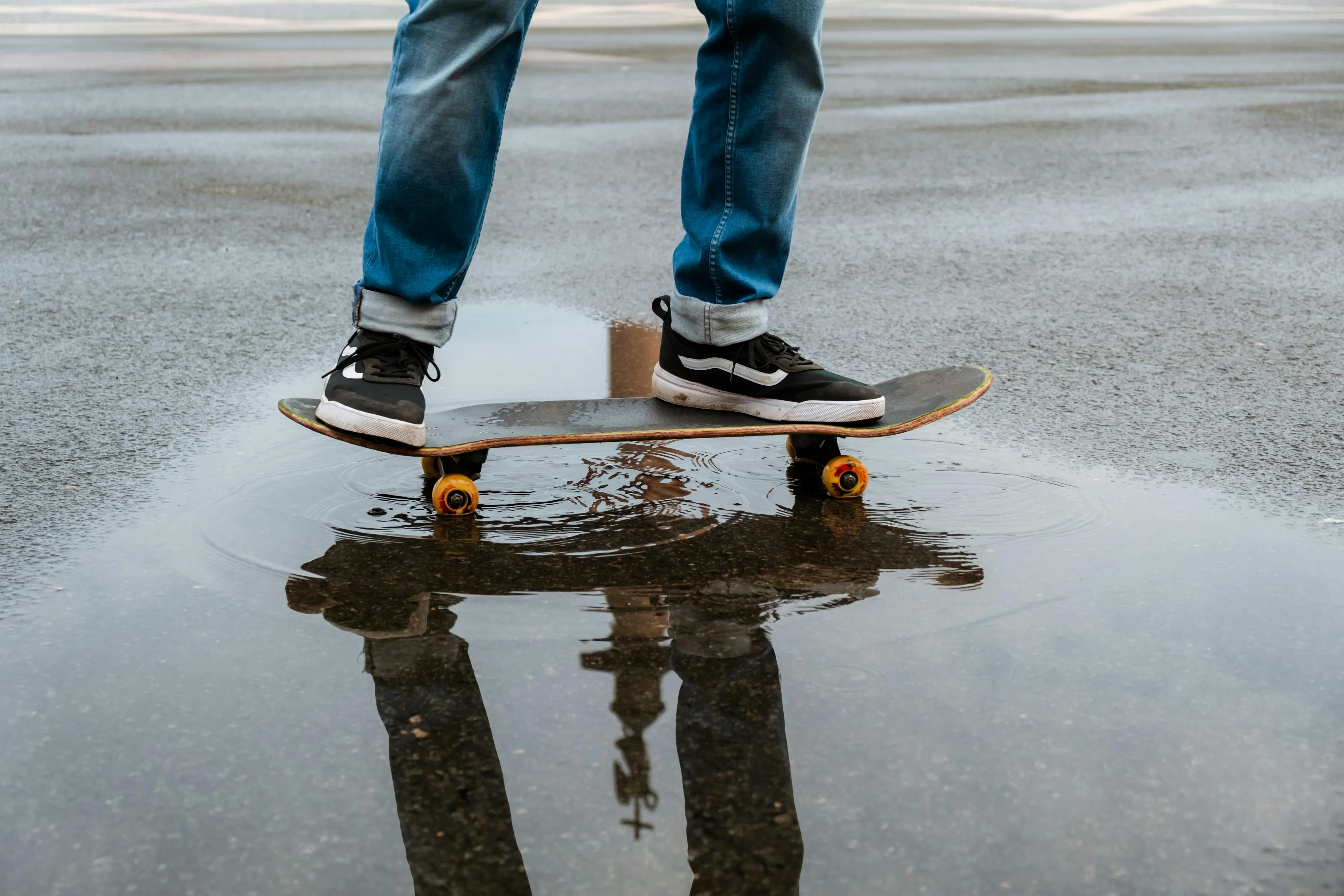 Person standing on a skateboard with sneakers near a water puddle, illustrating science general knowledge concepts.