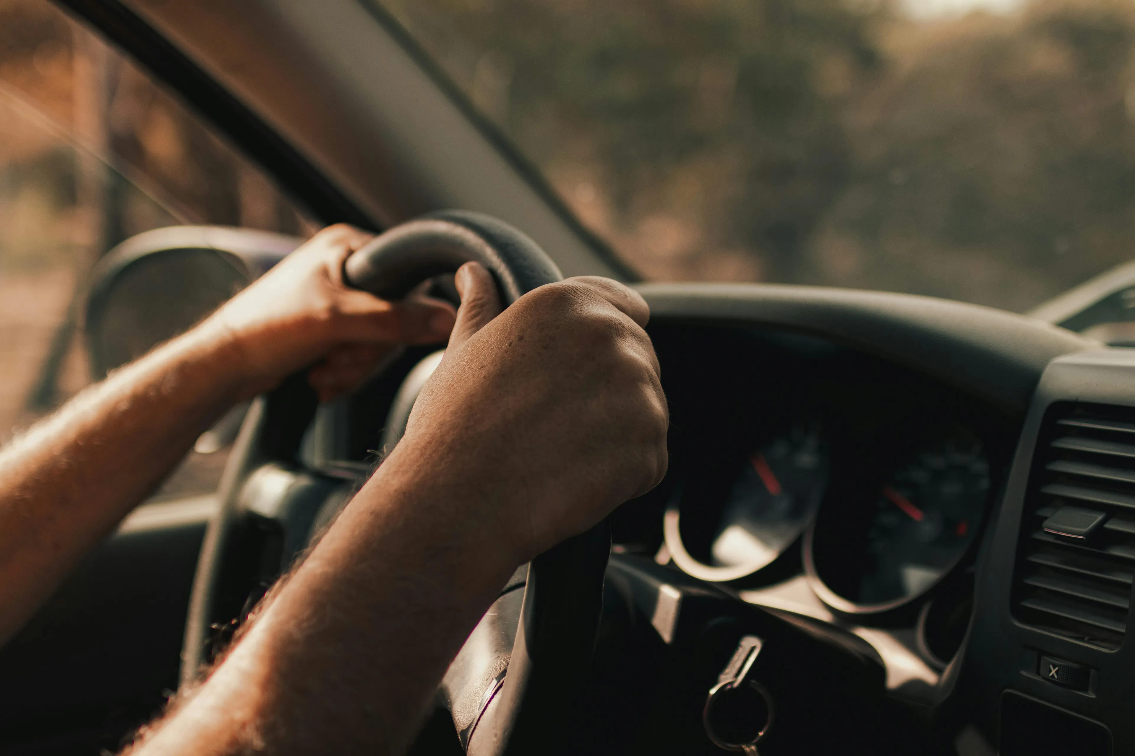 Hands gripping steering wheel inside moving car illustrating inertia in science general knowledge concept.