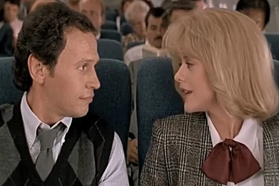 Harry and Sally sitting next to each other on an airplane, engaging in conversation during a scene from When Harry Met Sally.