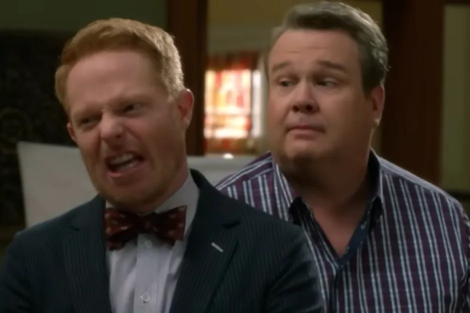 Two men indoors, one wearing a bow tie with an animated expression, unrelated to Brokeback Mountain couple image.