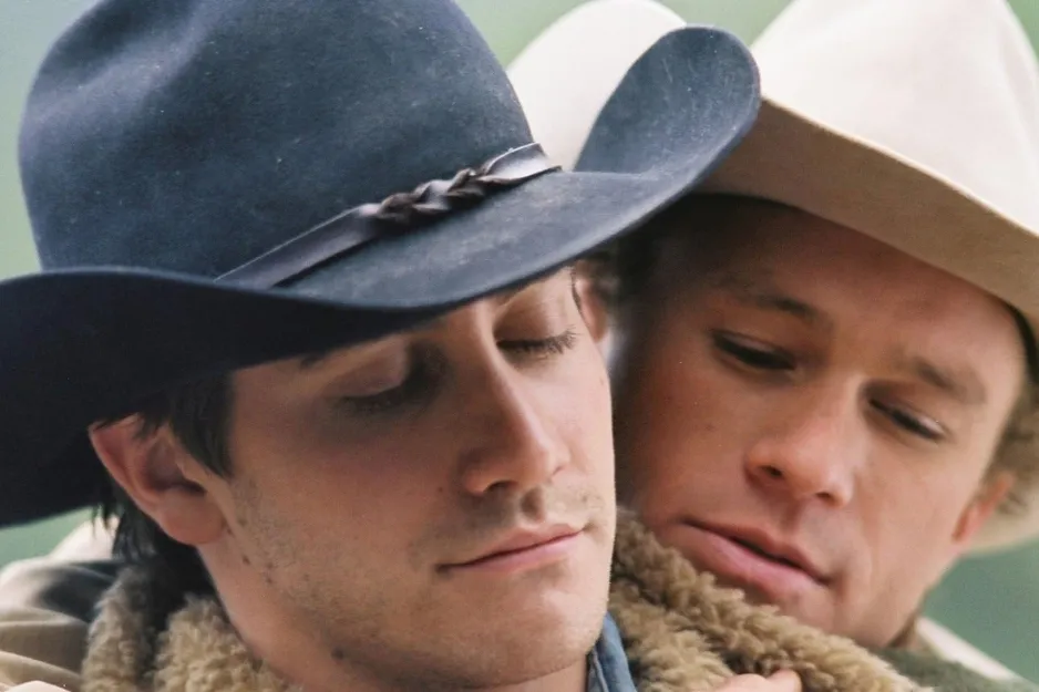 Couple from Brokeback Mountain wearing cowboy hats in an intimate close-up scene outdoors.