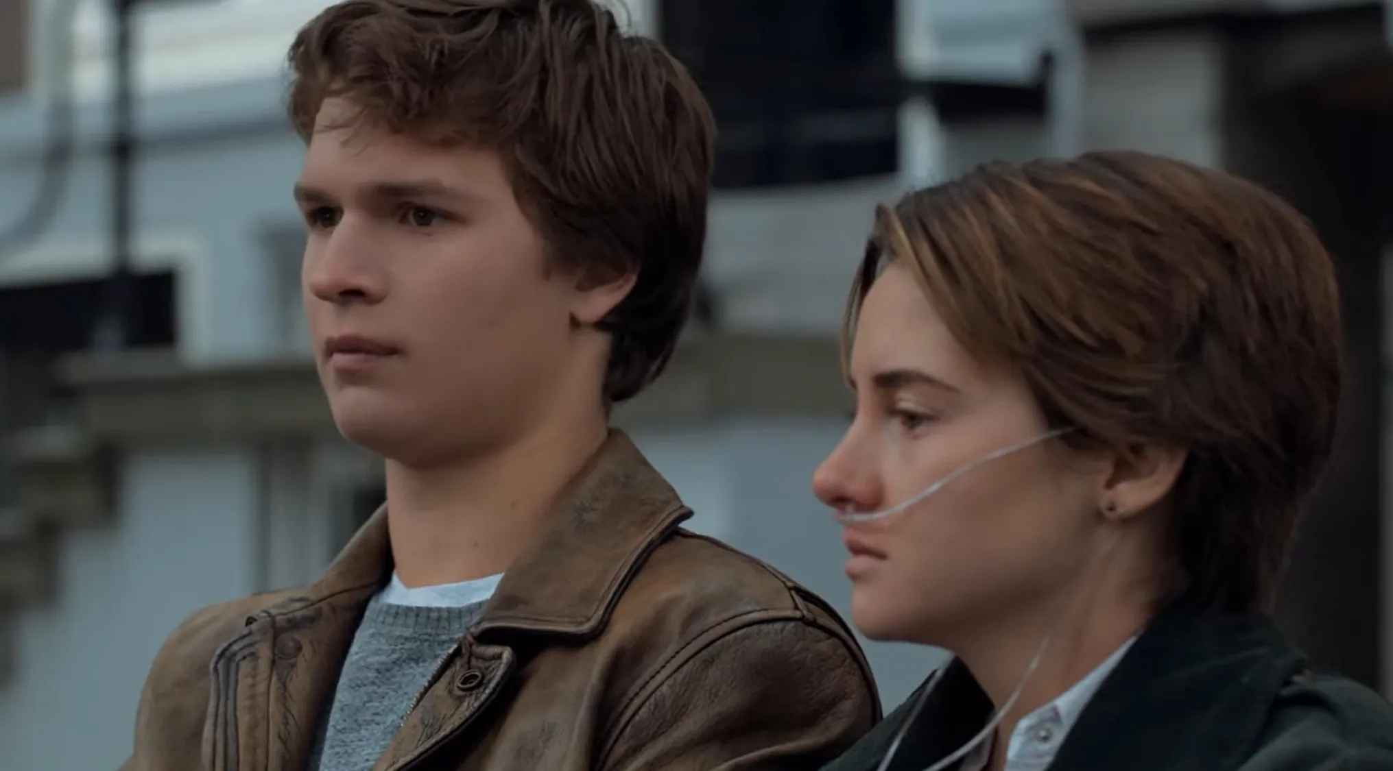Film depiction of a fictional couple with a young man in a leather jacket and a woman using an oxygen tube outdoors