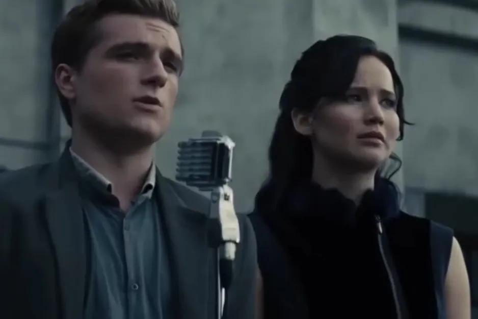 A couple from The Vampire Diaries standing near a vintage microphone outdoors with serious expressions.