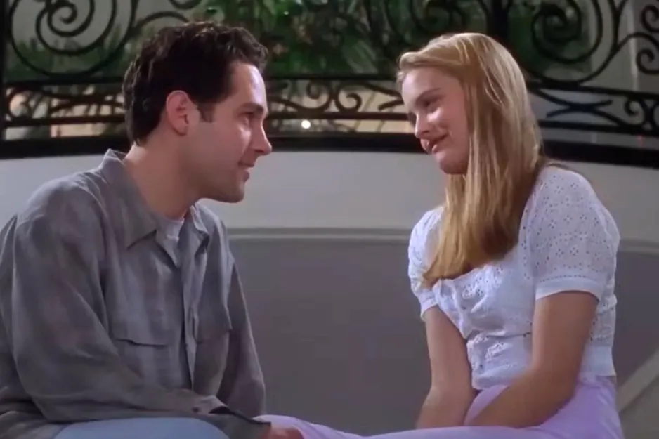 Two characters from Eyes Wide Shut sitting and smiling at each other in a softly lit indoor setting.