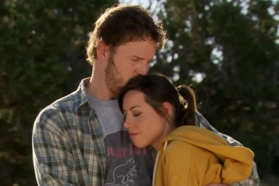Couple embracing outdoors with eyes closed, showing affection in a gentle moment focused on the Friends couple.