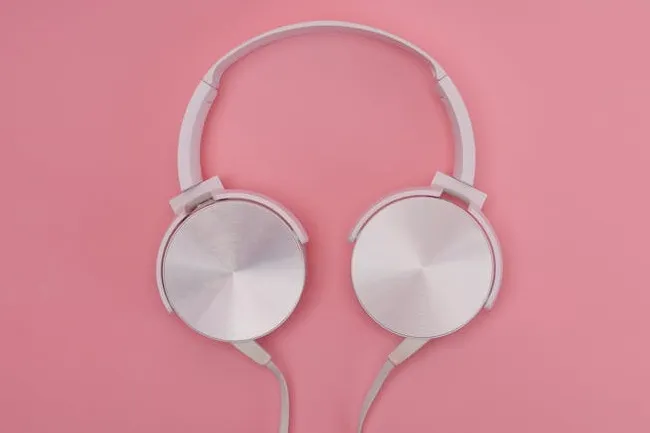 Silver headphones with round ear cups placed on a pink background, ideal for choosing something for your bag.