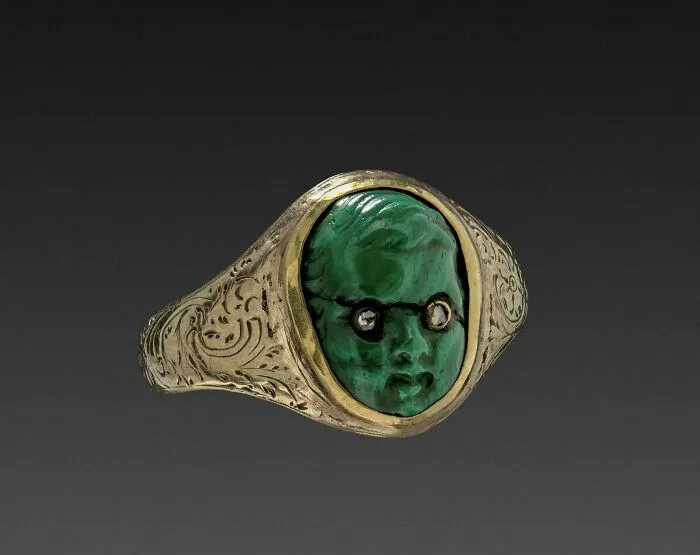 A Cherub Carved In Malachite, With Inset Diamond Eyes, Mounted Over A Gold Ring. United States, Late 19th Century