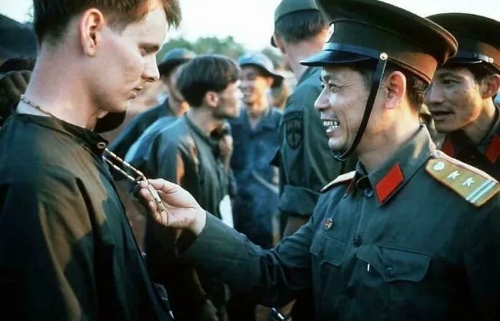 A North Vietnamese Army Officer Laughs At The Peace Symbol Necklace Of A Captured American Soldier, North Vietnam, 1973