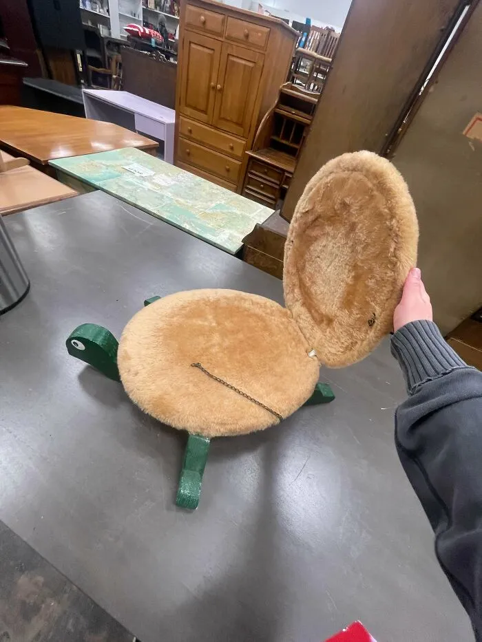 Hand opening a furry turtle-shaped footstool, showcasing questionable DIY projects from online.