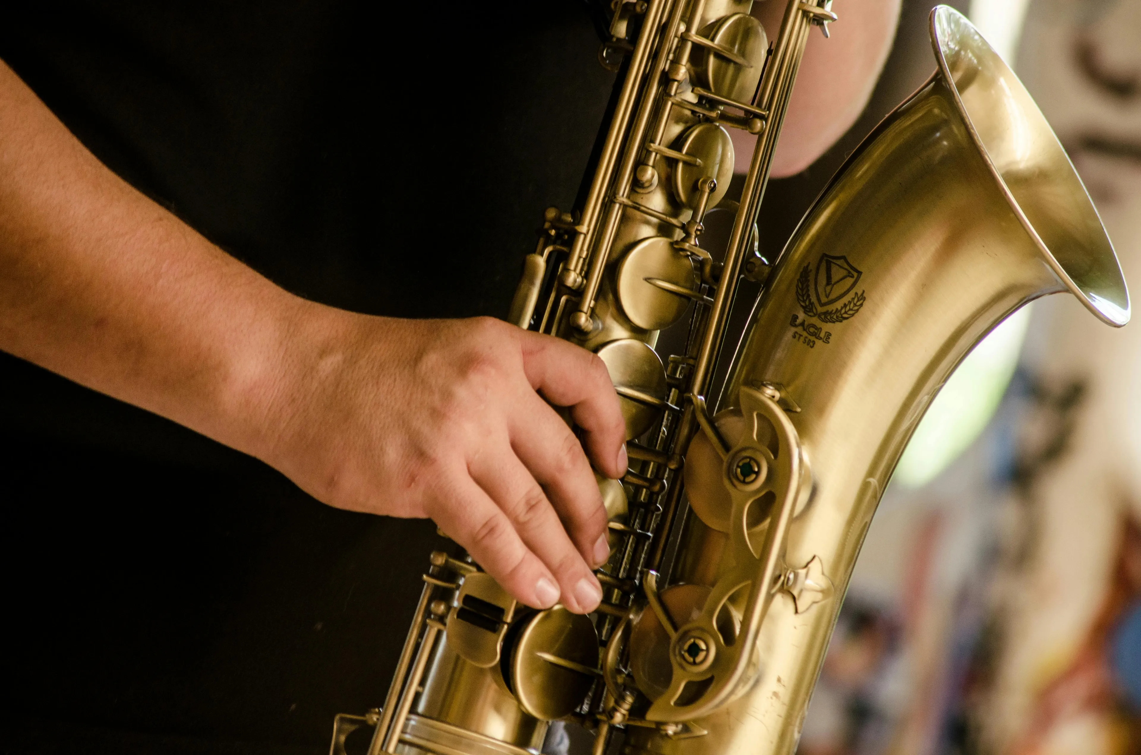 Close-up of a person playing a saxophone, enjoying listening to jazz as a relaxing rainy day activity.