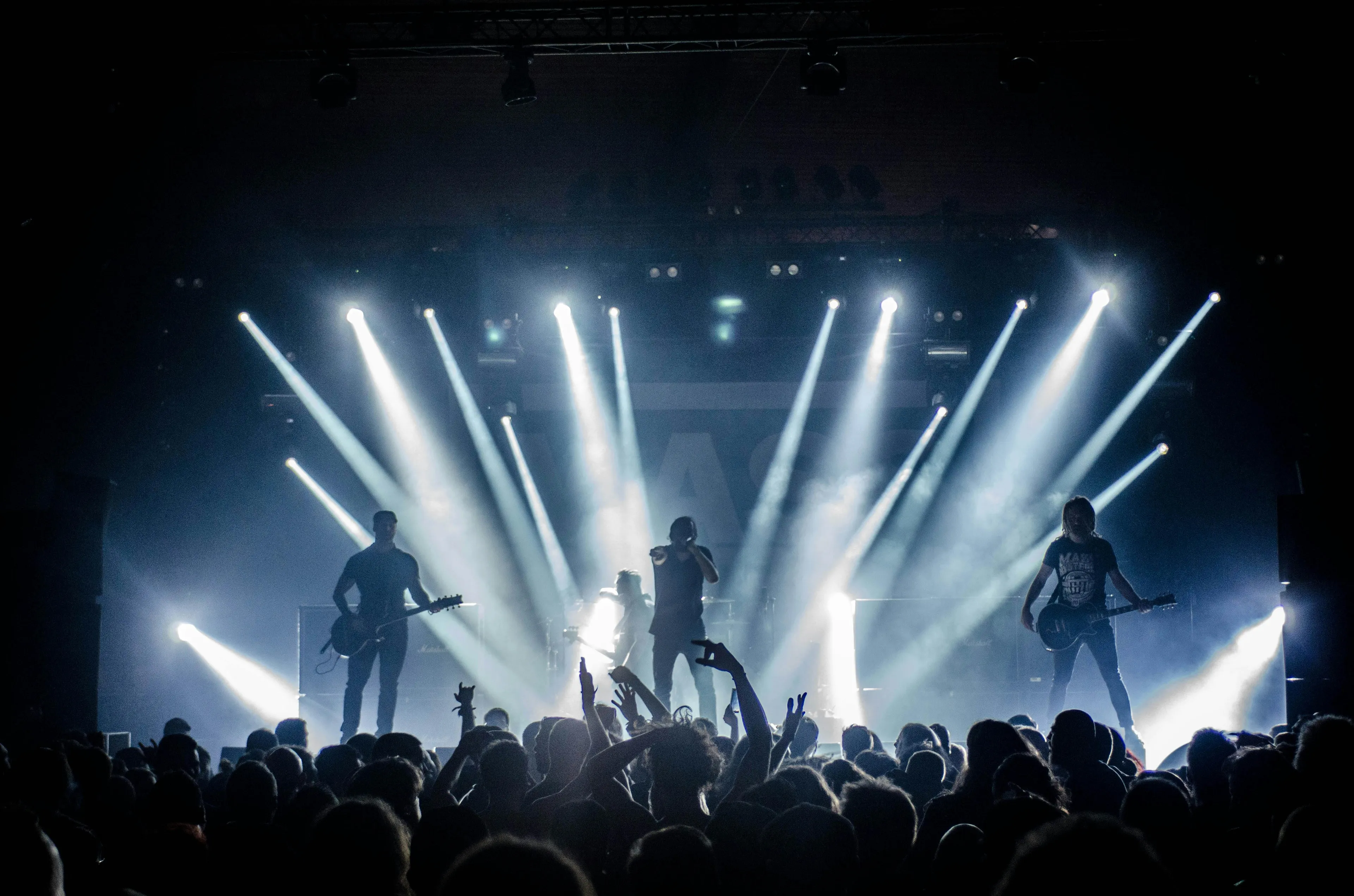 Stage lights mixing red green and blue beams to create bright white light during a live concert performance.