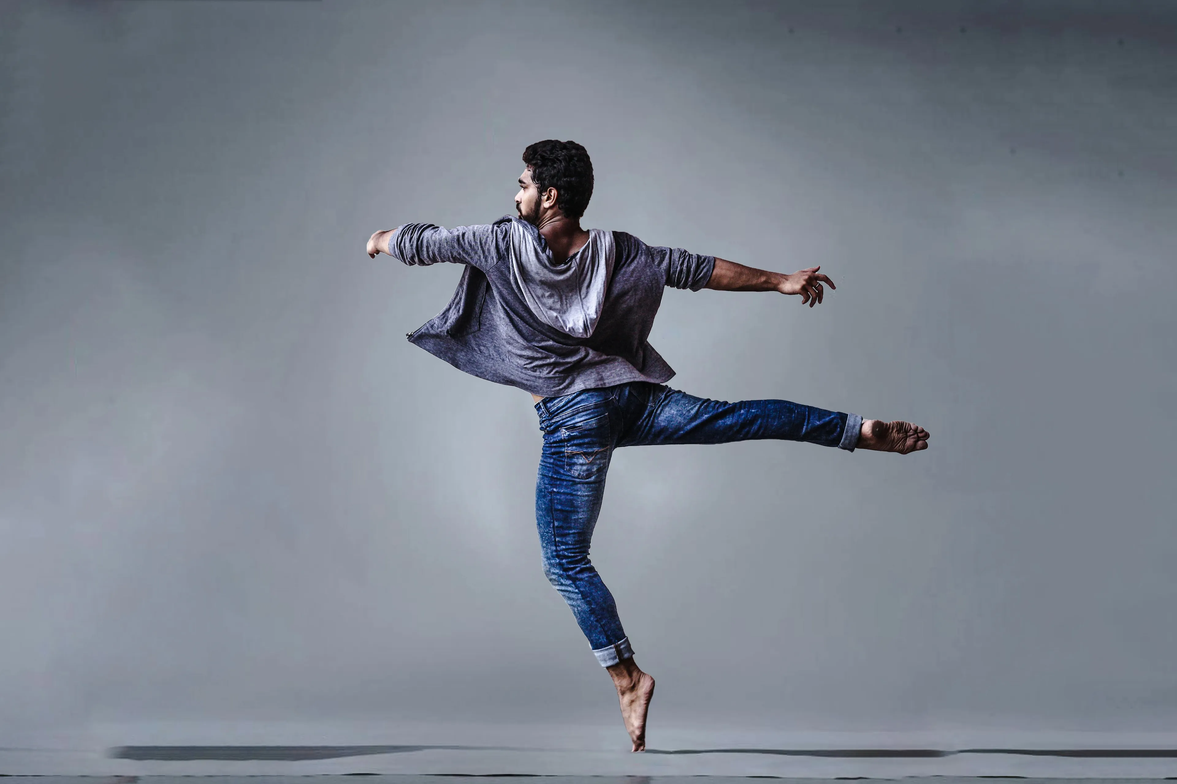 A male dancer spins with arms extended wearing casual clothes, demonstrating science general knowledge concepts.