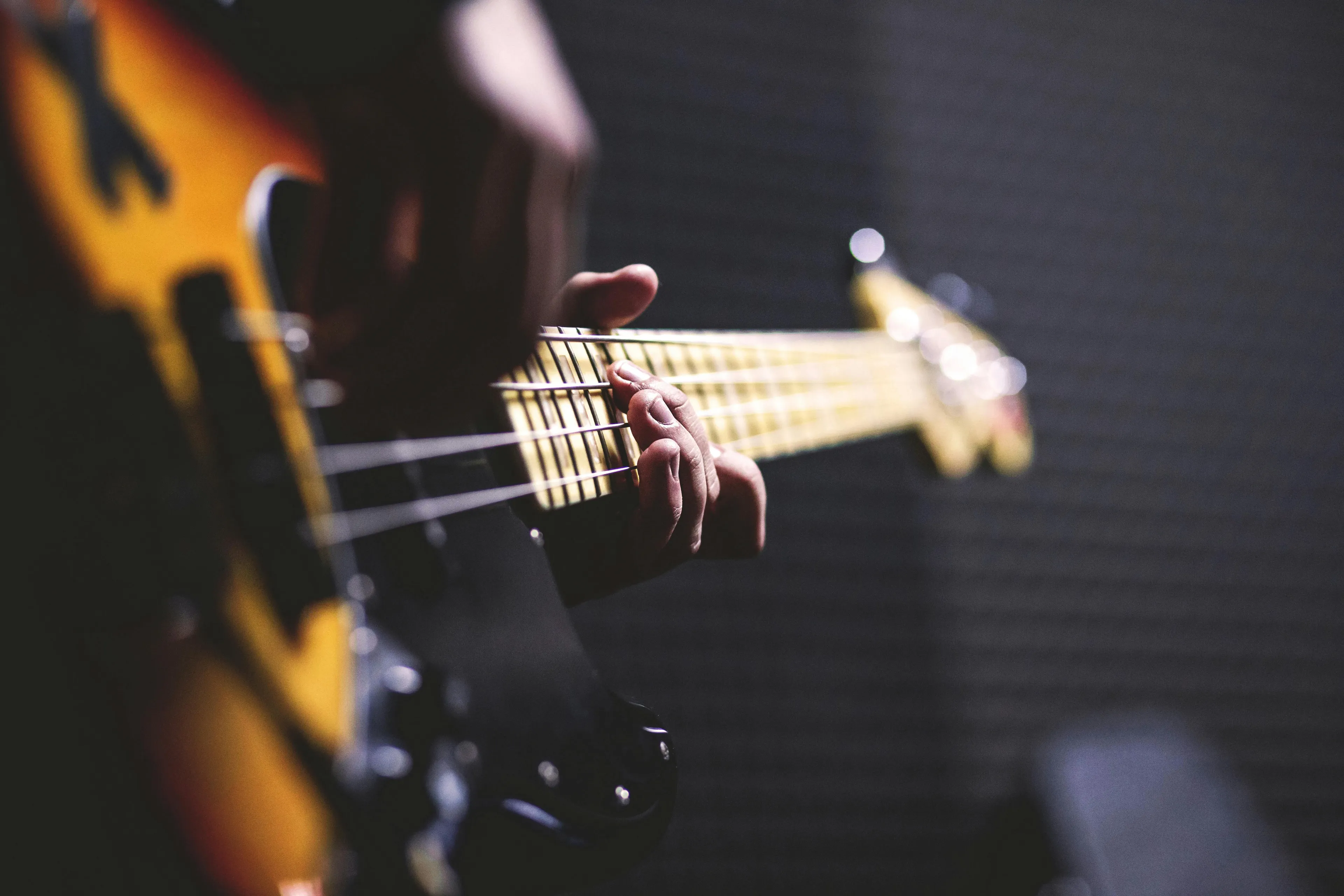 Close-up of a guitarist playing an electric guitar demonstrating energy transformation in music performance with amplifier.