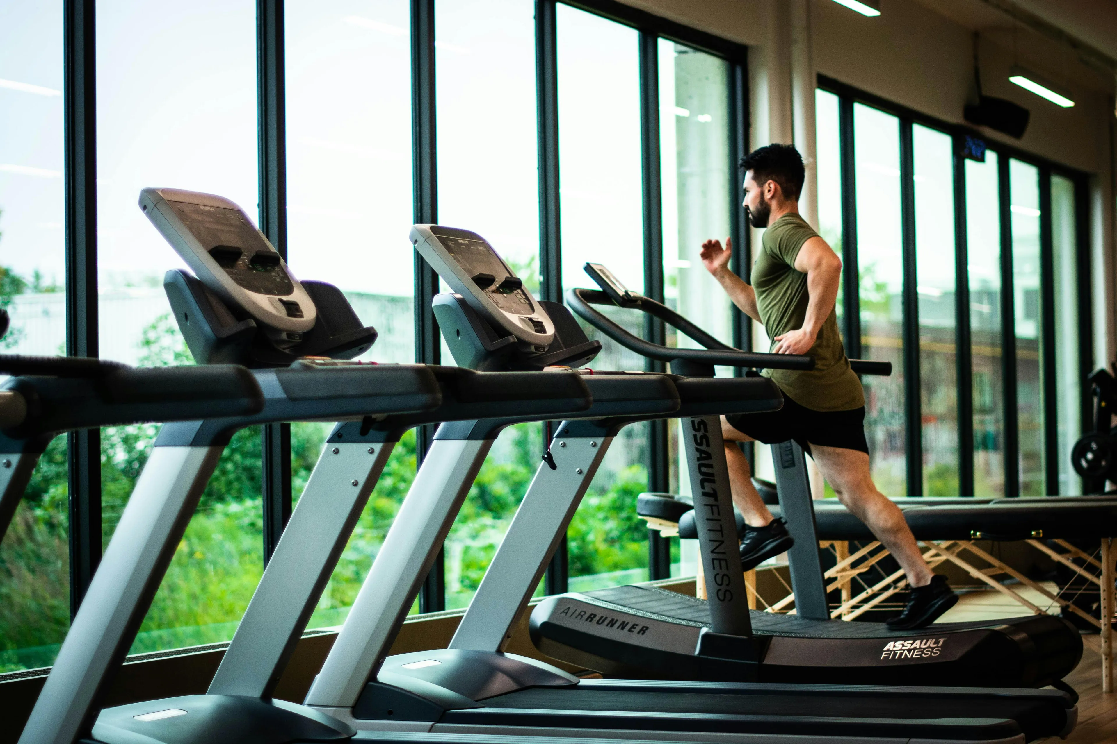 Man running on treadmill in gym showing muscles producing lactic acid during exercise in a fitness center.