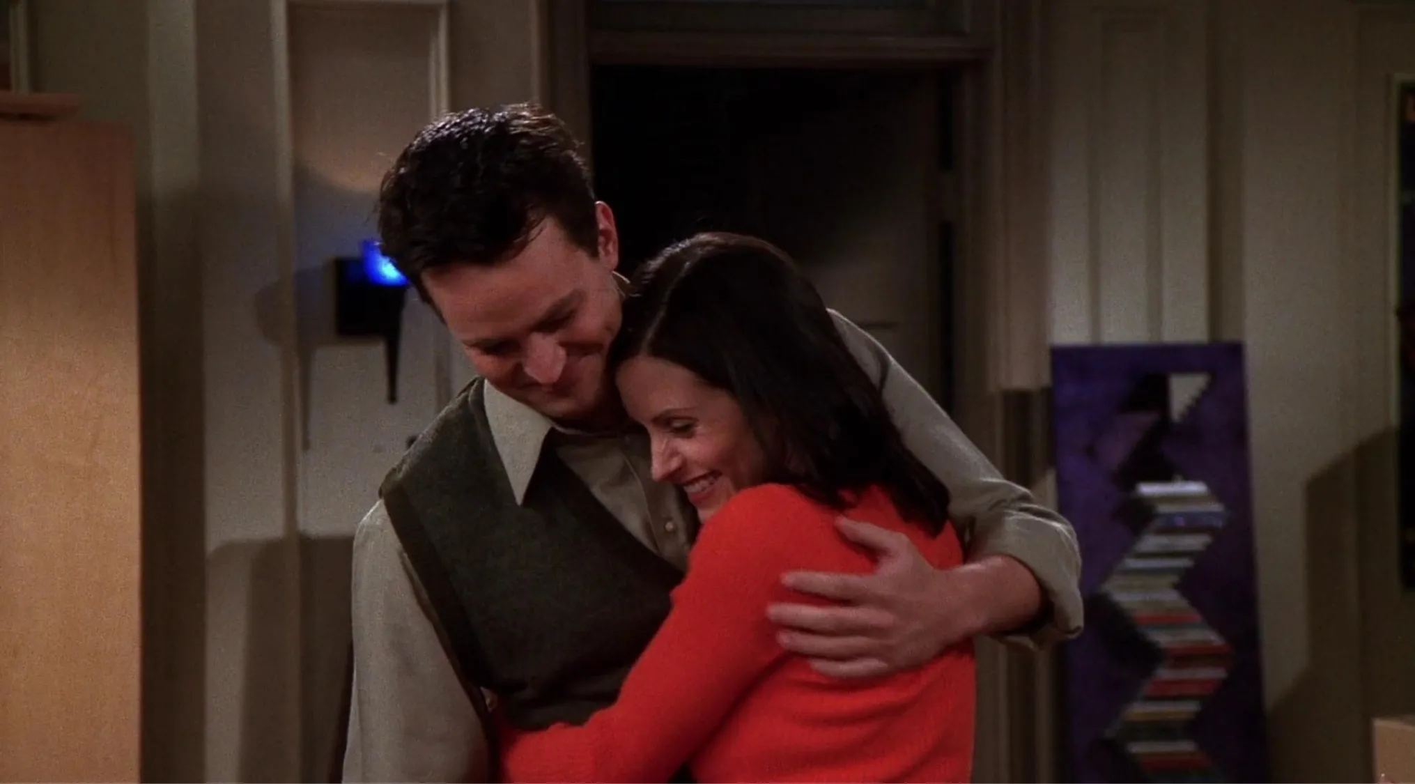Monica and Chandler hugging in an apartment scene, key moment for friends finding out about their relationship order.