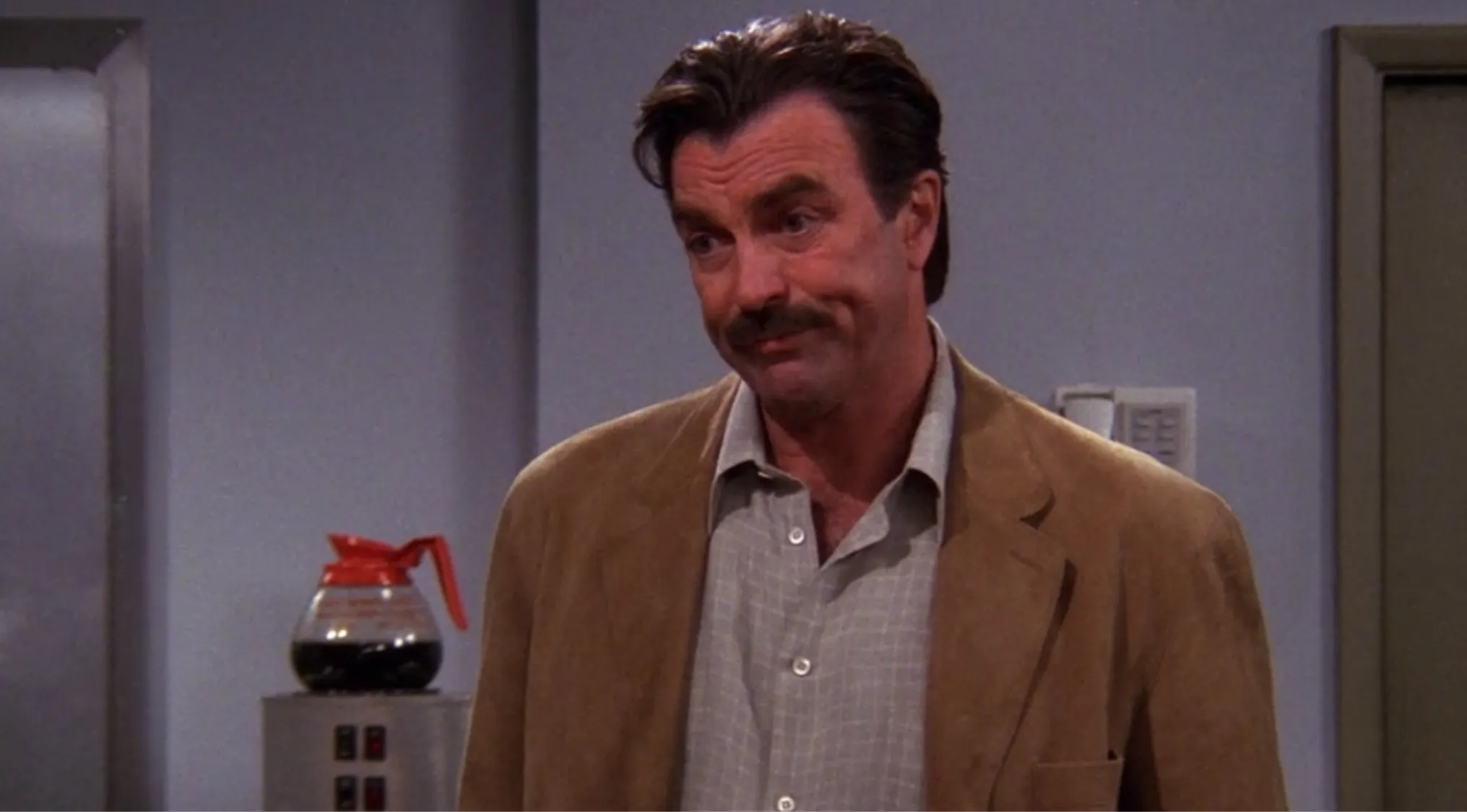 Richard from Friends with mustache and brown jacket in apartment setting, related to what kind of doctor he is.