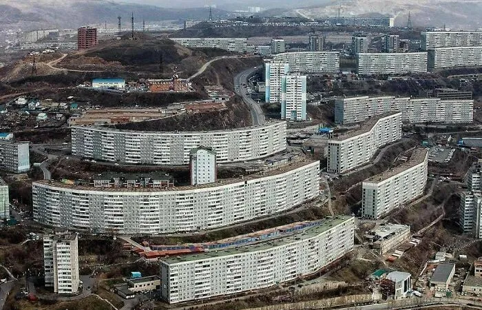Dystopian urban hell with large, monotonous apartment blocks clustered in a bleak, industrial modern cityscape.