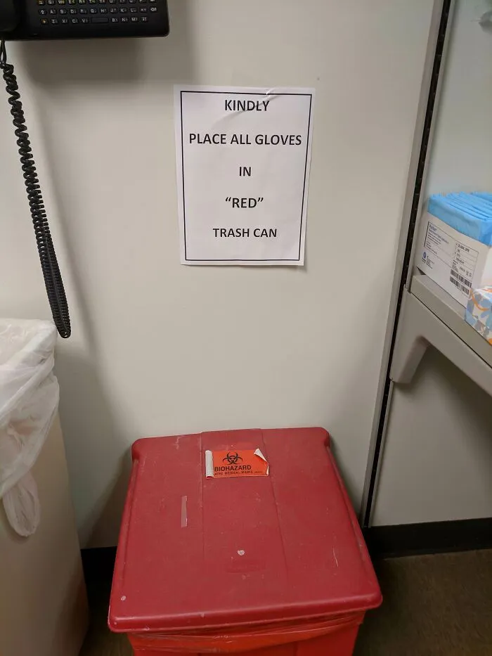 Sign on wall humorously using quotation marks around red above a red biohazard trash can in a medical or lab setting.