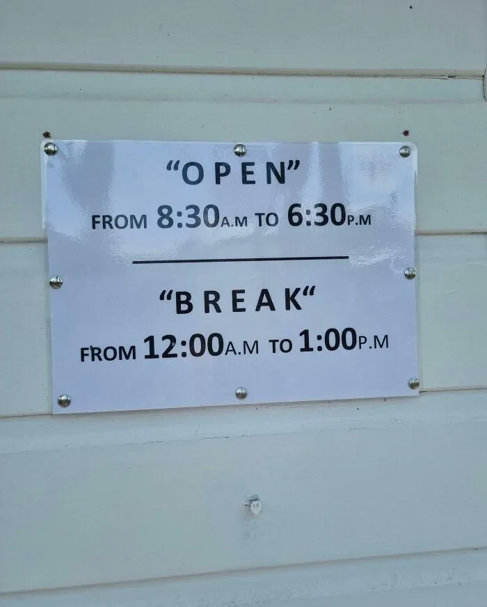 Sign with quotation marks around words open and break, making the hours look hilariously suspicious on a white wall.