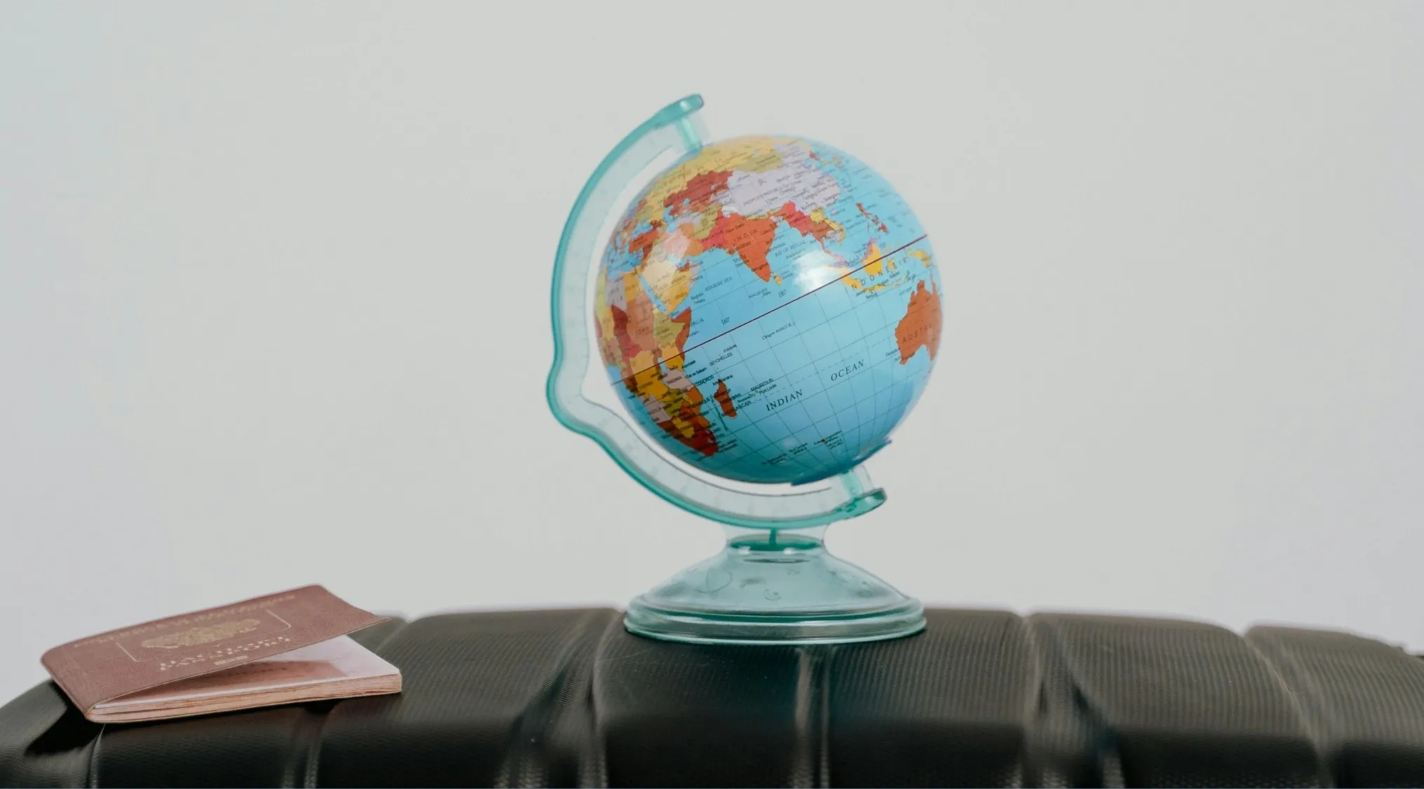 Small globe on suitcase with passports, representing geography edition and connection between Haiti, Quebec, and Belgium.