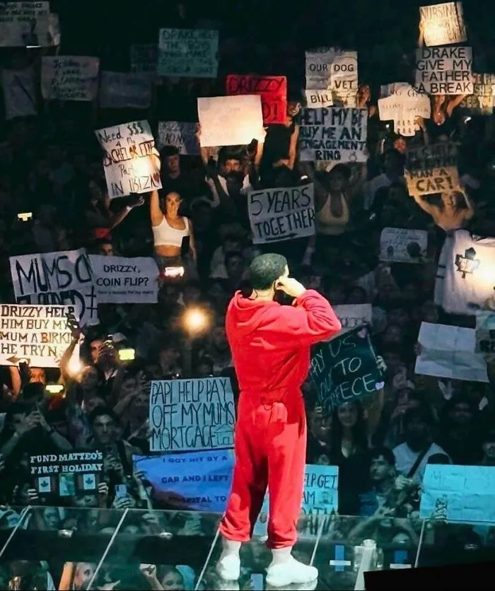 Una foto tomada en el concierto de Drake en Australia: fans con carteles pidiéndole favores (monetarios) a Drake.