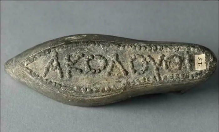 An ancient lead shoe sole stamped with Greek lettering, showcased among unique historical finds.
