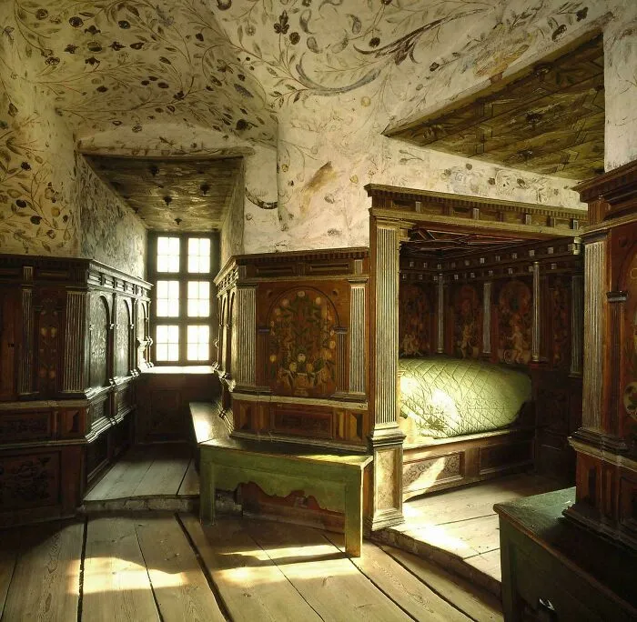 An ornate historical bedroom with wooden paneling and a canopy bed showing historical finds.