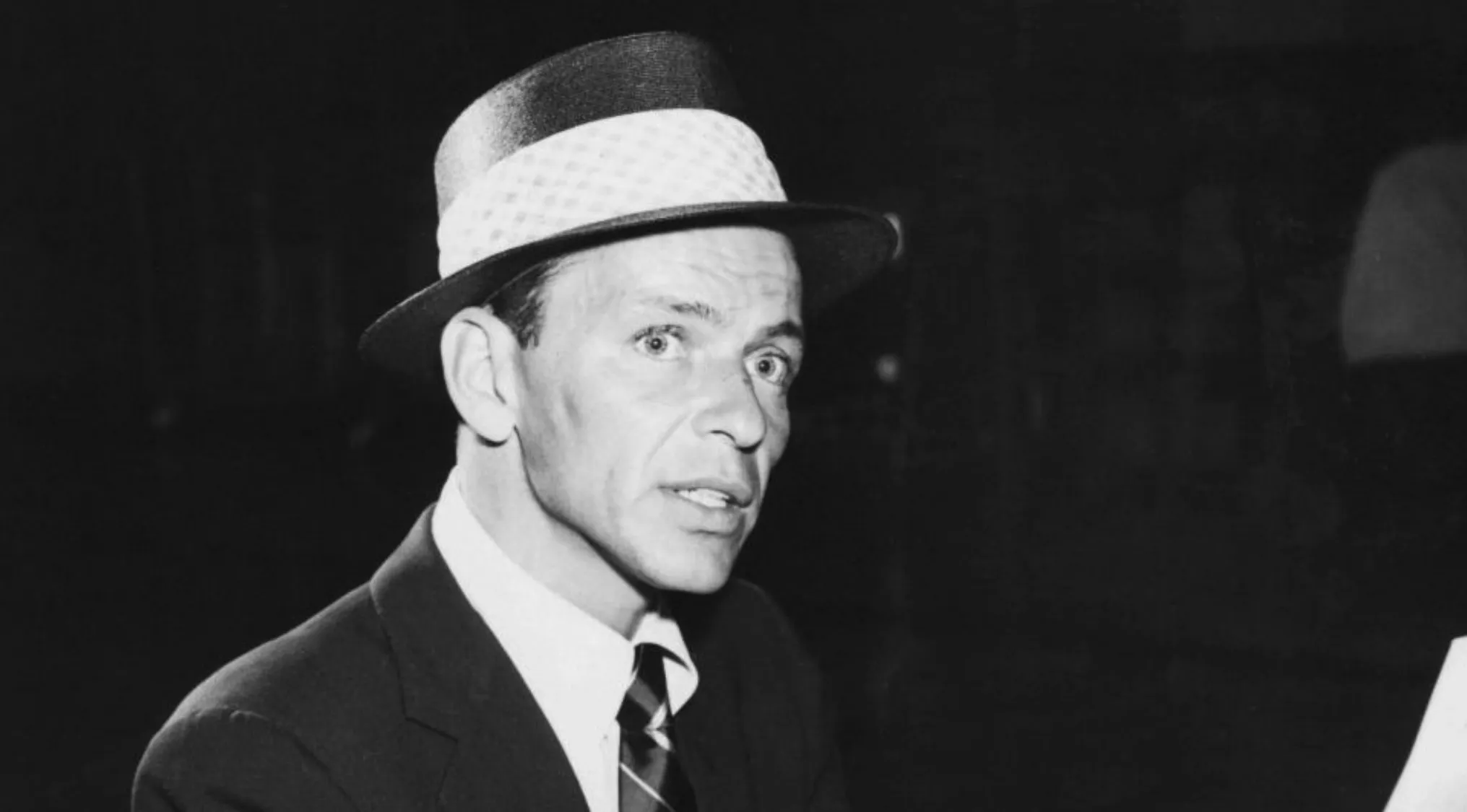 Frank Sinatra wearing a hat and suit in a black and white photo focused on his facial expression for last words quiz.