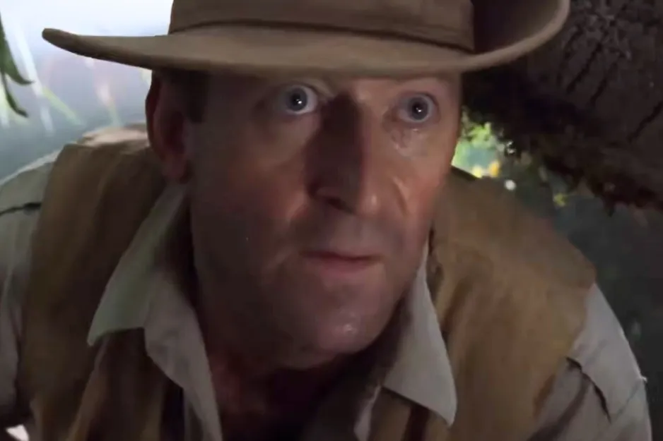 Robert Muldoon from Jurassic Park wearing a hat and vest, looking intensely at something off-screen in a jungle setting.
