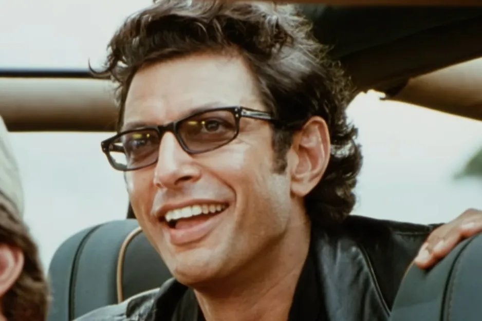 Jurassic Park character with glasses smiling inside a vehicle, a scene from the iconic Jurassic Park movie.