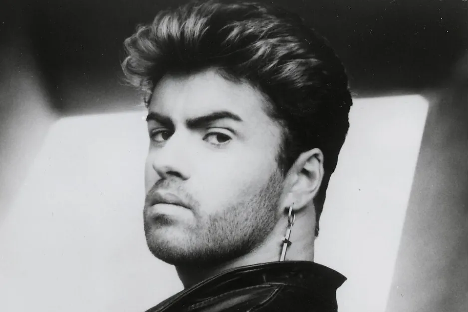 Black and white portrait of George Michael with styled hair and cross earring, looking seriously over his shoulder.