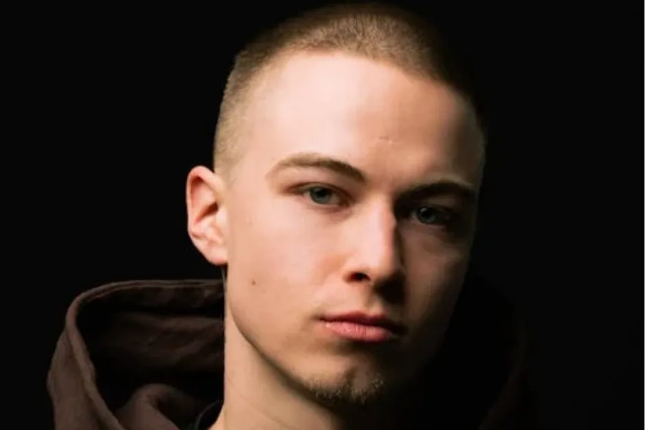 Young man with a buzz cut hairstyle against a dark background, showcasing the popular 1980s men's haircut.