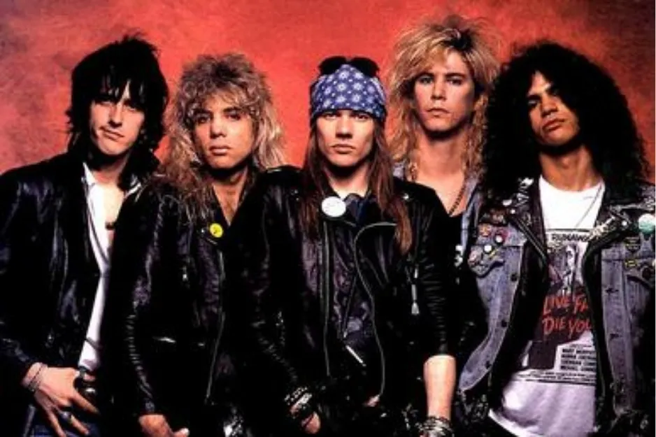 Band Guns N’ Roses posing in leather jackets with 1980s rock style and bandanas against a red background.
