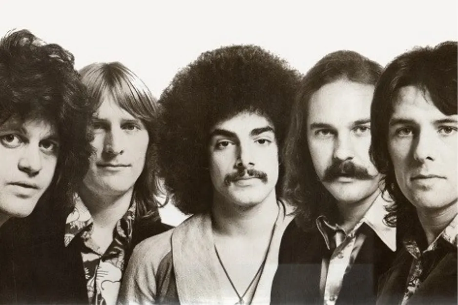 Band Journey members posing for a black and white portrait photo featuring five men with 1970s hairstyles and fashion.