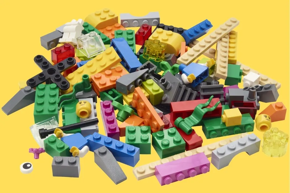 Assorted colorful LEGO bricks and pieces scattered on a bright yellow background.