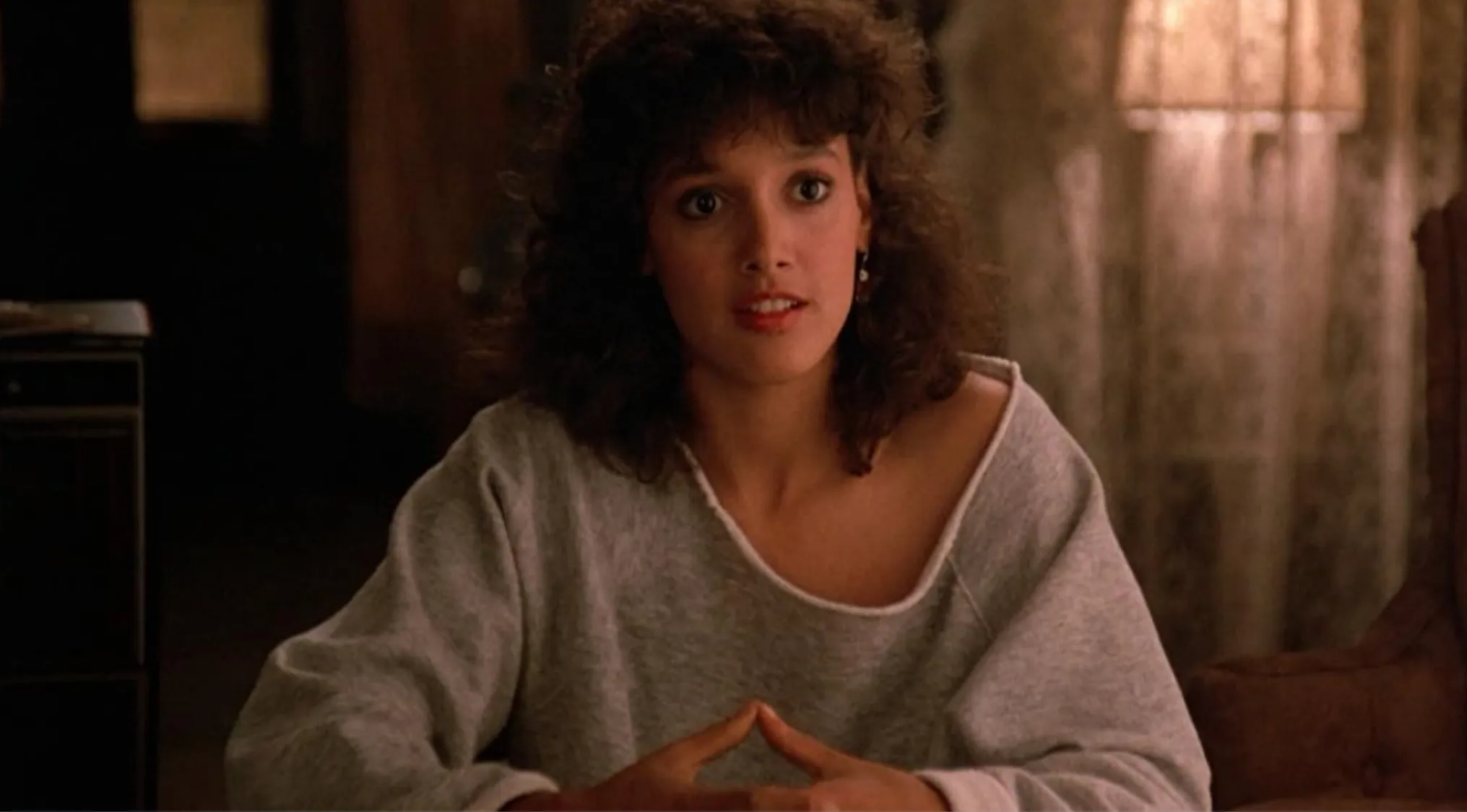 Young woman in a gray sweatshirt from 80s pop culture scene discussing the hit song featured in Flashdance.