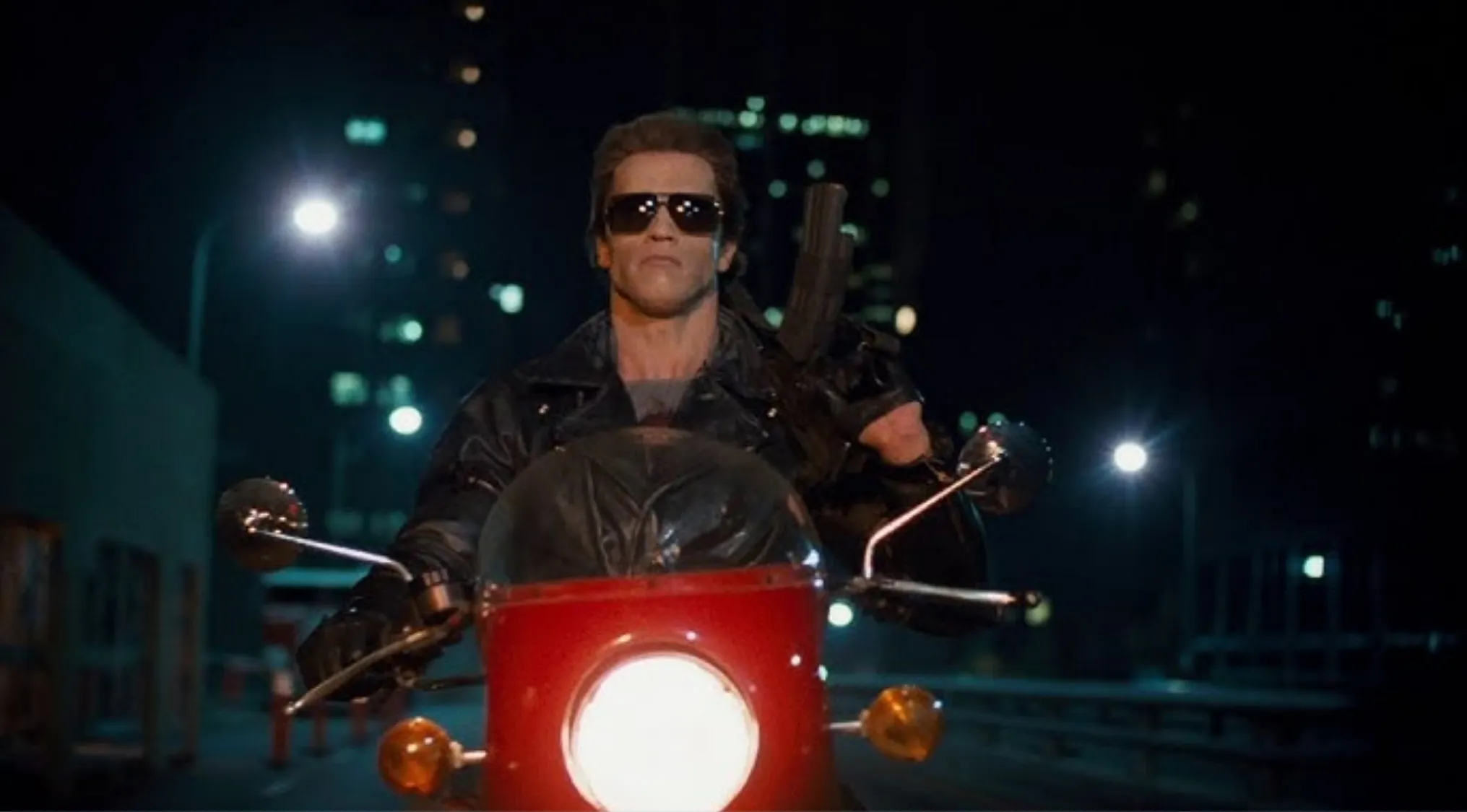 Arnold Schwarzenegger as The Terminator riding a red motorcycle at night, key 80s pop culture and film icon.