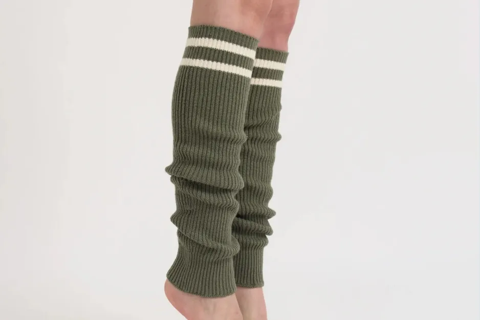 Leg warmers in green knit with white stripes worn on legs against plain white background showing 1980s fashion trend.