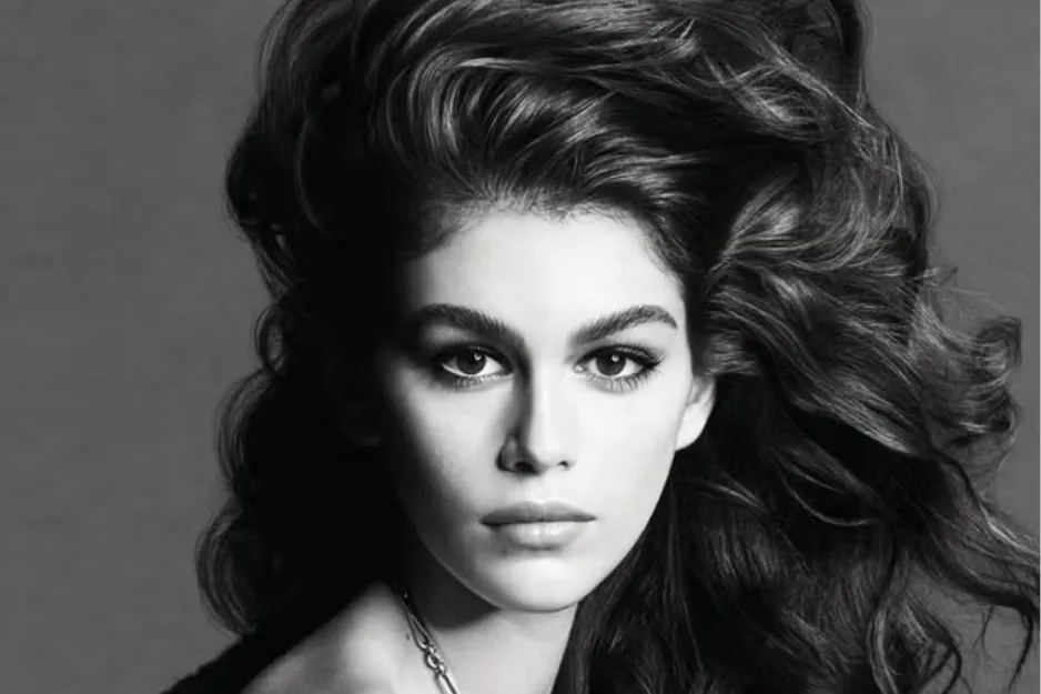 Woman with big voluminous hair styled in the iconic 1980s trend, posing with a serious expression in black and white.