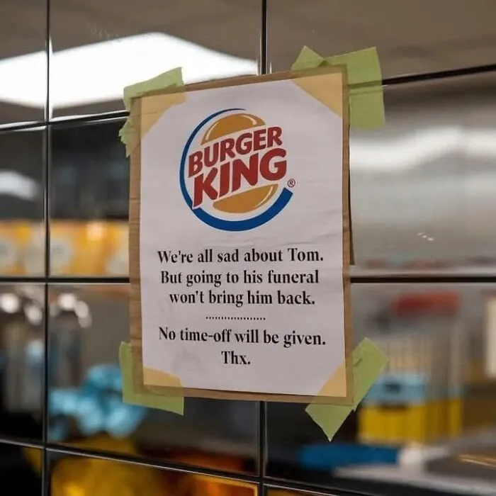 Burger King sign on a wall humorously denying time off for an employee's funeral, exposing uncultured and ignorant behavior.
